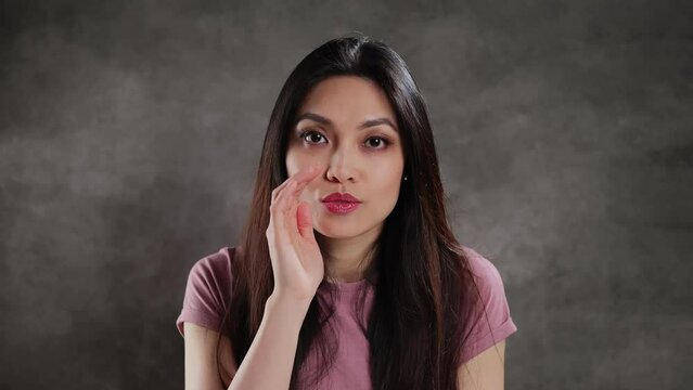 Young Asian woman in a studio whispering something - extreme slow motion
