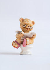 Porcelain bear wears glasses to read the news while using the toilet in the bathroom, hygiene