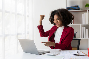 Obraz premium African american girl working at office with laptop and financial document calculator excited about success with arms raised and to celebrate victory with smile.
