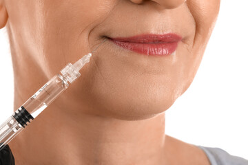 Mature woman receiving filler injection on white background, closeup