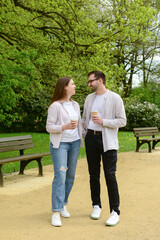 Beautiful happy loving couple walking in park and drinking coffee on spring day