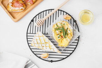 Grid with tasty baked Camembert cheese on grey background