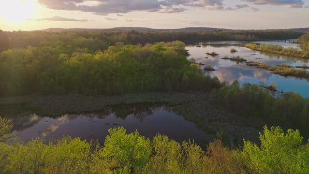 Dolly back reveals sunset over forest treetops at Lake Sequoyah, White River, near Fayetteville Arkansas - Aerial