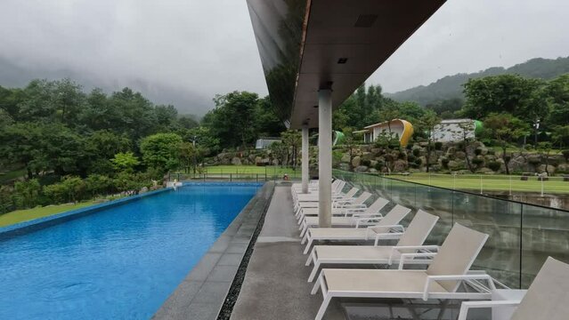 Empty Glamping Resort With Infinity Pool and Deck Chairs During Rainstorm in South Korea - panning