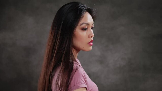Young Asian woman in a studio posing for the camera - extreme slow motion