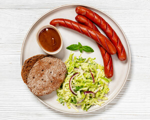 sausages with coleslaw salad, bbq sauce on plate