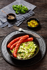 cooked sausages with coleslaw salad in black bowl