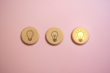 3 wooden blocks with light bulb icon on pink background, sparking creative concept.