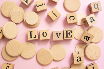 Wooden blocks with leather word LOVE on pink background, creative concept of finding love