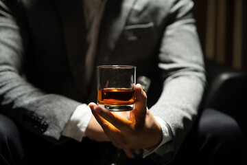 Businessman sitting and holding glass of whiskey