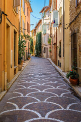 Fototapeta na wymiar Ornate mosaic street pavement between traditional old houses near the covered provencal farmers market in old town or Vieil Antibes, South of France