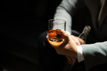 Businessman sitting and holding glass of whiskey