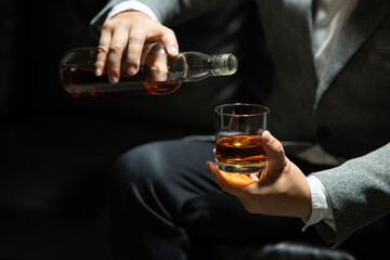 Businessman sitting and holding glass of whiskey