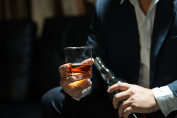 Businessman sitting and holding glass of whiskey