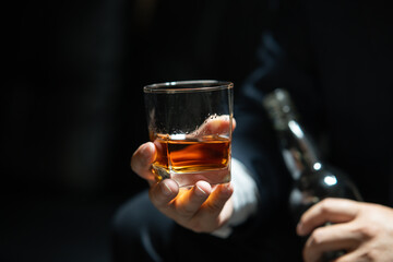 Businessman sitting and holding glass of whiskey