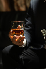 Businessman sitting and holding glass of whiskey