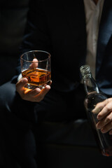 Businessman sitting and holding glass of whiskey