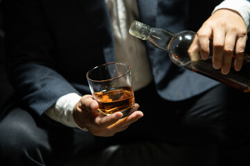Businessman sitting and holding glass of whiskey