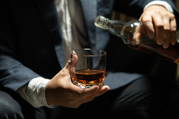 Businessman sitting and holding glass of whiskey