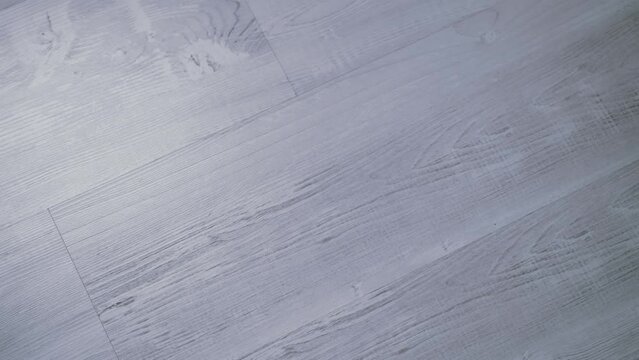 Gray laminate flooring parquet floor tracking shot from left to right close-up, wooden table, for background.