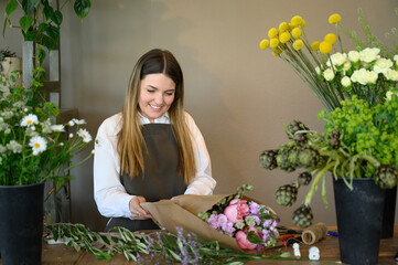 Smiling woman wrapping flowers bouquet in shop