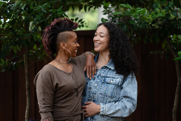 Fototapeta premium With their arms wrapped around each other, two women hug in a candid moment expressing their love, communication, and honesty with each other. They are lesbian, multiracial, and Black.