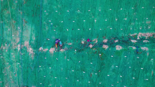 Ouvriers escaladant une falaise recouverte d'un filet vert sur un chantier de Bohol aux Philippines, Asie