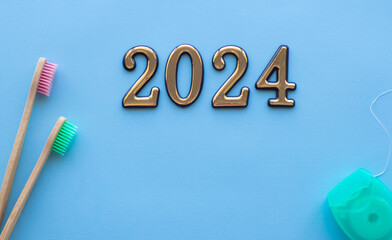 2024 and dental concept. Close up view of photo with 2024, dental floss and two wooden toothbrush...