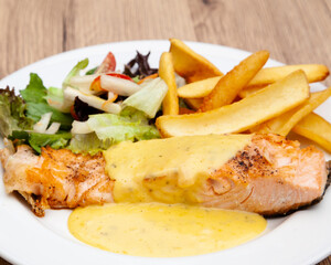 Salmon steak with fries, salad and hollandaise sauce