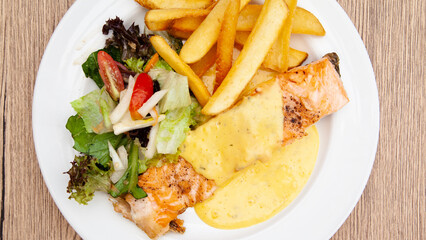Salmon steak with fries, salad and hollandaise sauce
