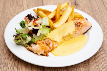 Salmon steak with fries, salad and hollandaise sauce