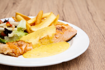 Salmon steak with fries, salad and hollandaise sauce