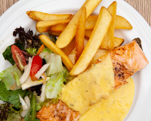 Salmon steak with fries, salad and hollandaise sauce