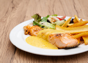 Salmon steak with fries, salad and hollandaise sauce