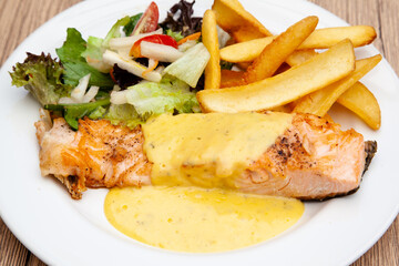 Salmon steak with fries, salad and hollandaise sauce