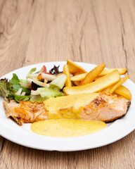 Salmon steak with fries, salad and hollandaise sauce