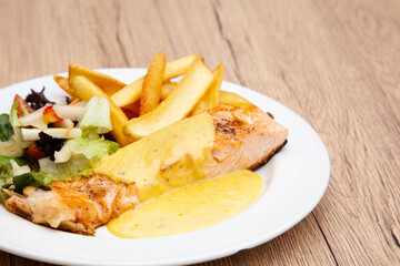 Salmon steak with fries, salad and hollandaise sauce