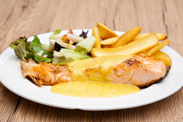 Salmon steak with fries, salad and hollandaise sauce