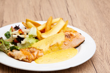 Salmon steak with fries, salad and hollandaise sauce