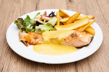 Salmon steak with fries, salad and hollandaise sauce