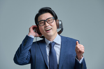 Middle-aged man wearing a headset and listening to music on his smartphone