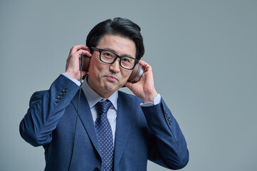 Middle-aged man wearing a headset and listening to music on his smartphone