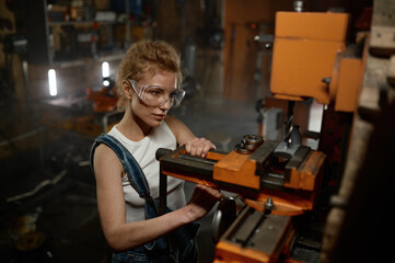 Woman wearing safety protective goggles working on milling and drilling machine