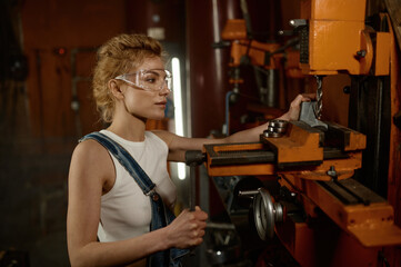 Woman wearing safety protective goggles working on milling and drilling machine