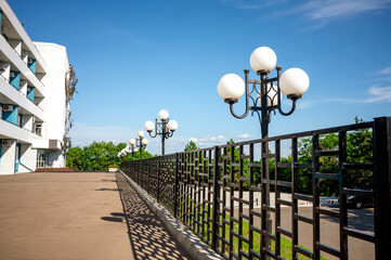 A row of street lights in a city park, an alley leading to a gazebo in the garden on a sunny summer...