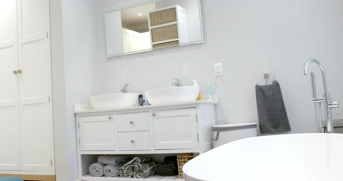 General view of bathroom with bathtub at home, mirror and washbasin, slow motion