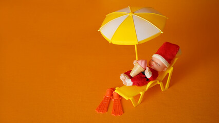  A baby dressed as Santa Claus lies in a sun lounger on the beach.  