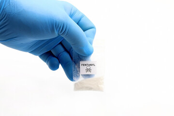 Blue glove holding a pouch of fentanyl, a potent opioid that causes overdose deaths - obrazy, fototapety, plakaty