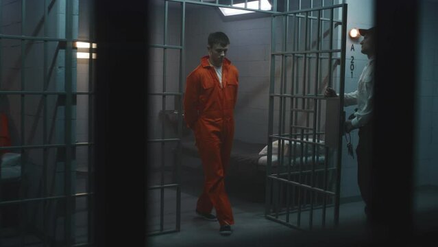 Prison officer opens prison cell with keys. Male prisoner in orange uniform and handcuffs fights with jailer. Another inmate strangles prison employee. Jail, detention center or correctional facility.