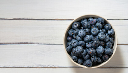top view of fresh blueberries in bowl on white wooden table